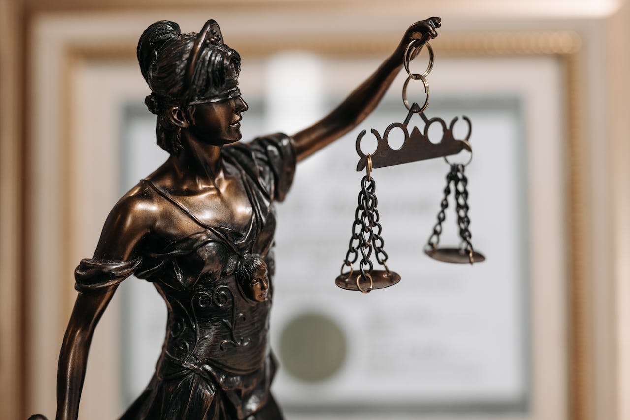 Services-03 Close-up of a bronze Lady Justice statue holding scales in an office environment.